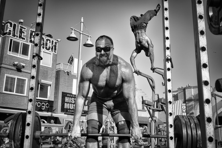People Honorable Mention Photo and caption by Dotan Saguy / National Geographic Travel Photographer of the Year Contest Muscle Beach Gym A weightlifter lifts a barbell loaded with heavy plates while a bodybuilder performs an aerial handstand at the Muscle Beach Gym in Venice Beach, CA.