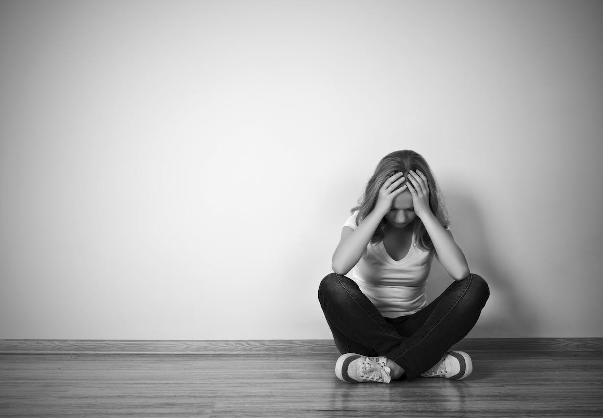 girl sits in depression on floor near the wall